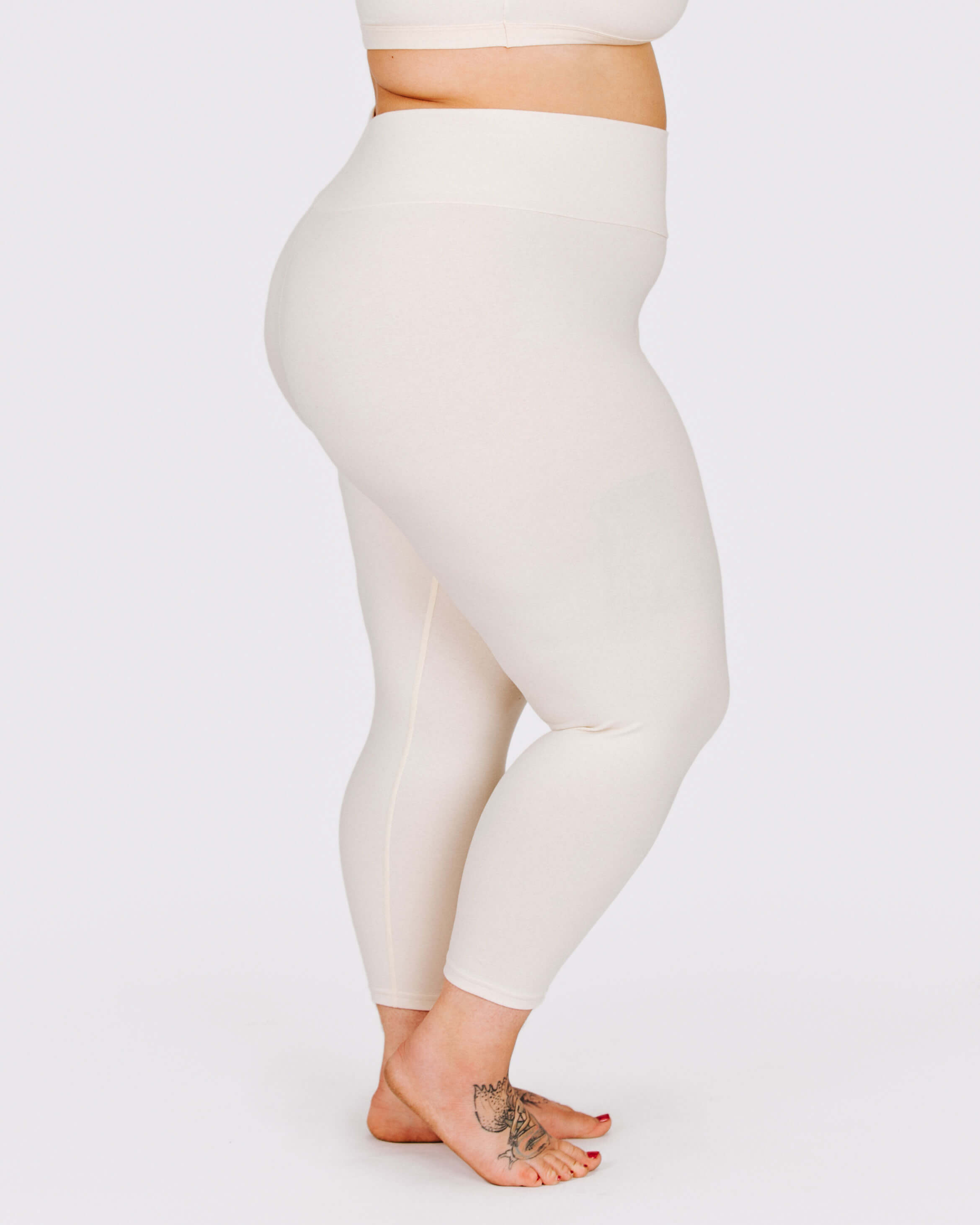 Person wearing cream leggings on a white background