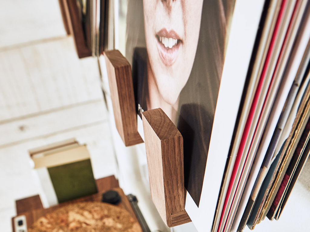 Wooden record holder with vinyl records and a photo album on a white surface.