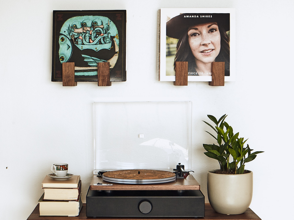 Turntable with vinyl records and a plant on a white wall