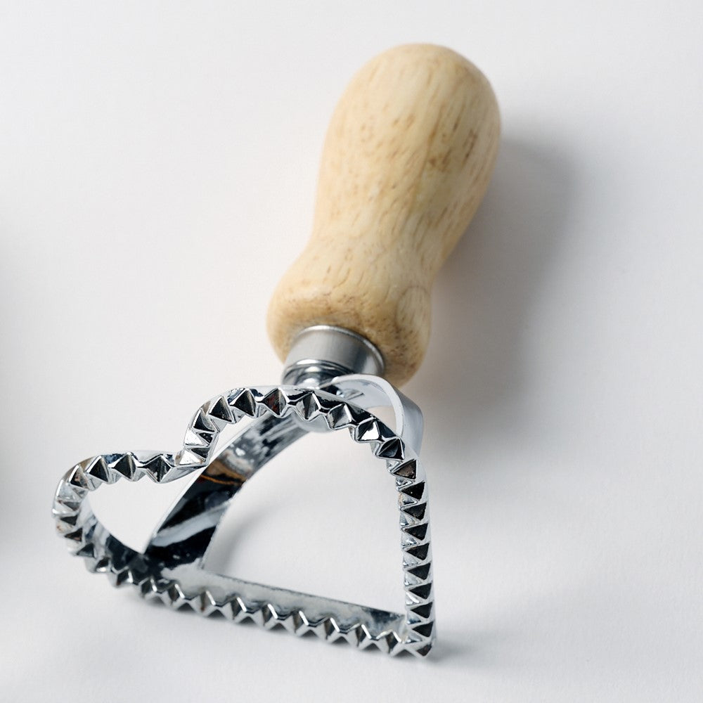 Metal cookie cutter with wooden handle on a white background