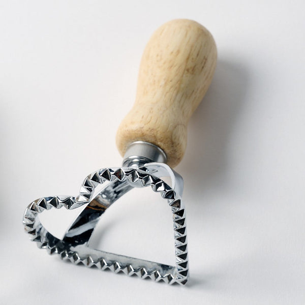 Metal cookie cutter with wooden handle on a white background