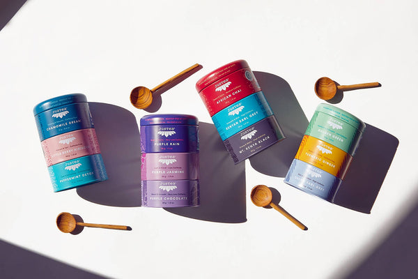 Colorful tins with wooden spoons on a white background