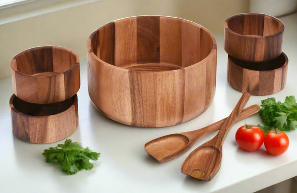 Set of wooden kitchen utensils including a bowl, cups, and spoons on a white surface with vegetables.