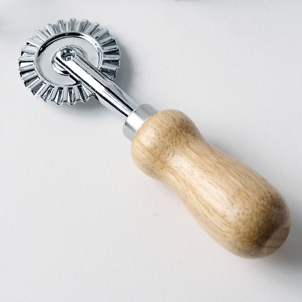 Dough roller with wooden handle and metal wheel on a white background