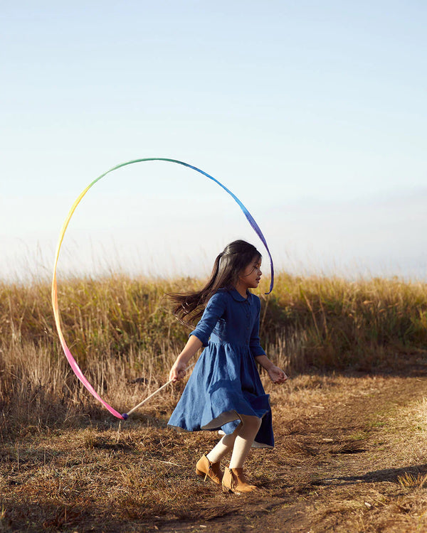 Woman in a blue dress playing with a colorful hoop in a field