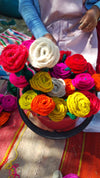 Colorful yarn flowers in a bowl with a person in the background.