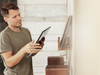 Man holding a tablet in a room with a shelf of vinyl records.