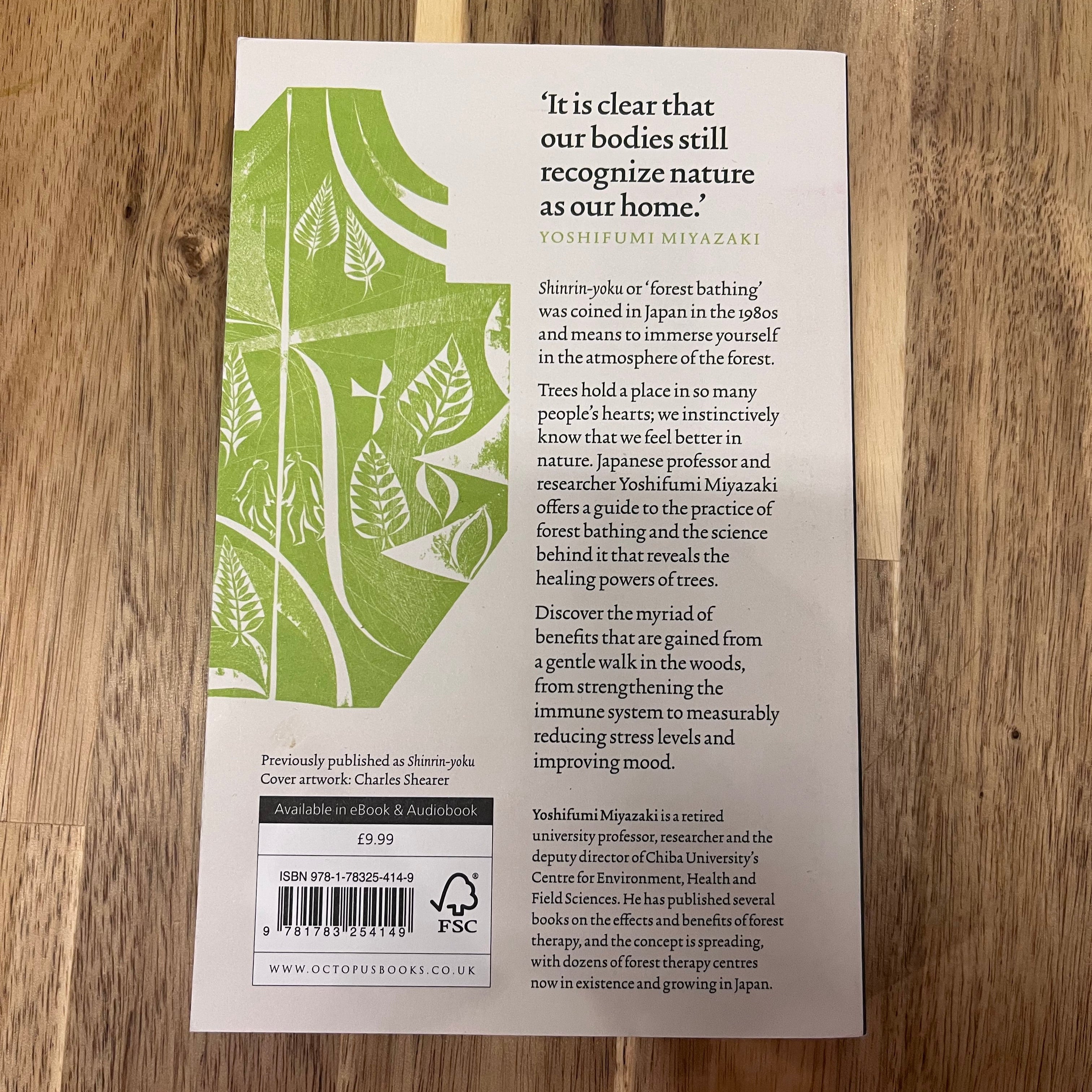 Book back cover with text and green leaf design on a wooden surface