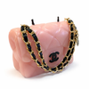 Pink Chanel handbag with a gold and black chain strap on a white background