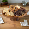 Wooden cake stand with assorted cookies on a wooden table
