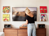 Person standing in front of a television with decorative items on the wall