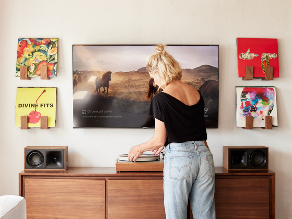 Person standing in front of a television with decorative items on the wall