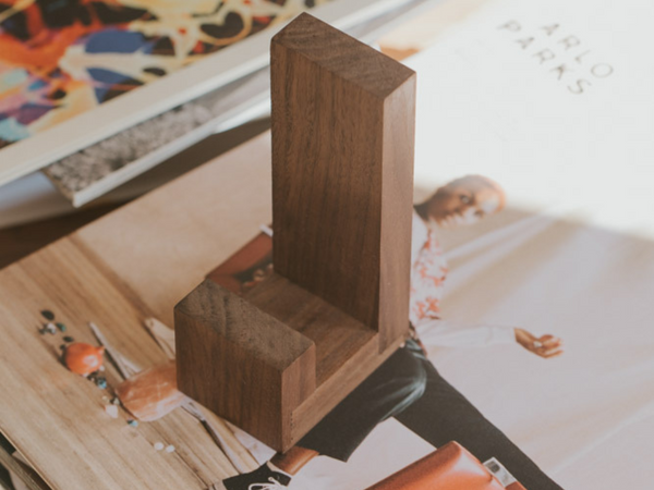Wooden bookend on a surface with magazines in the background