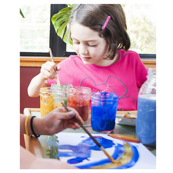Child painting with colorful paints at a table