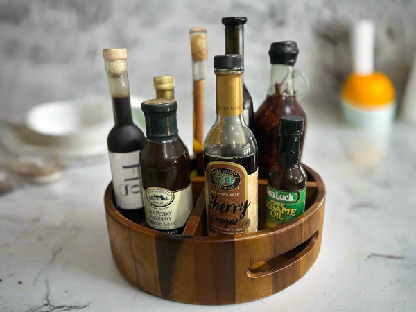 Wooden bottle holder with various condiment bottles on a marble surface