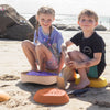 Two children sitting on beach toys at the beach.