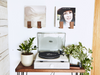 Turntable on a wooden table with plants and wall art in the background
