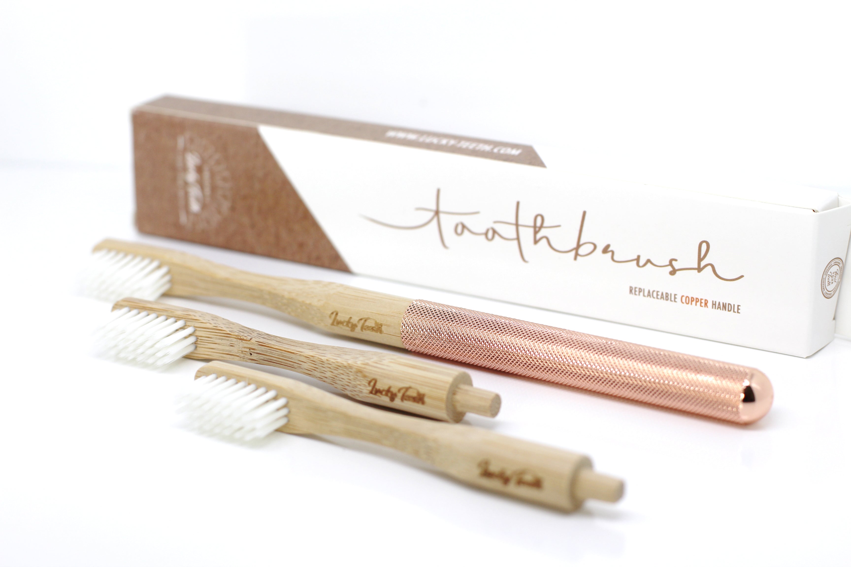 Set of bamboo and rose gold toothbrushes with packaging on a white background