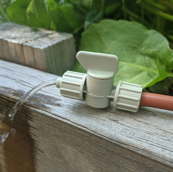 Garden hose nozzle with water flowing on a wooden surface