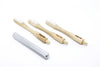 Three wooden toothbrushes with bristles and a metal tool on a white background