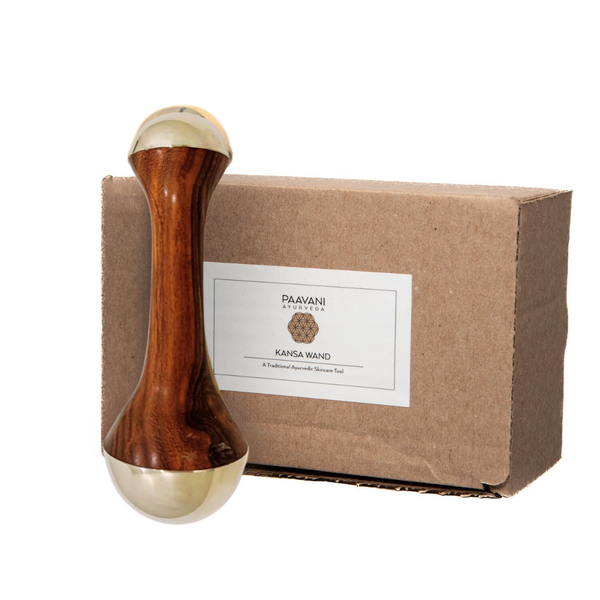 Wooden and gold Kansa Wand with a brown box labeled 'Paavani Ayurveda' on a white background