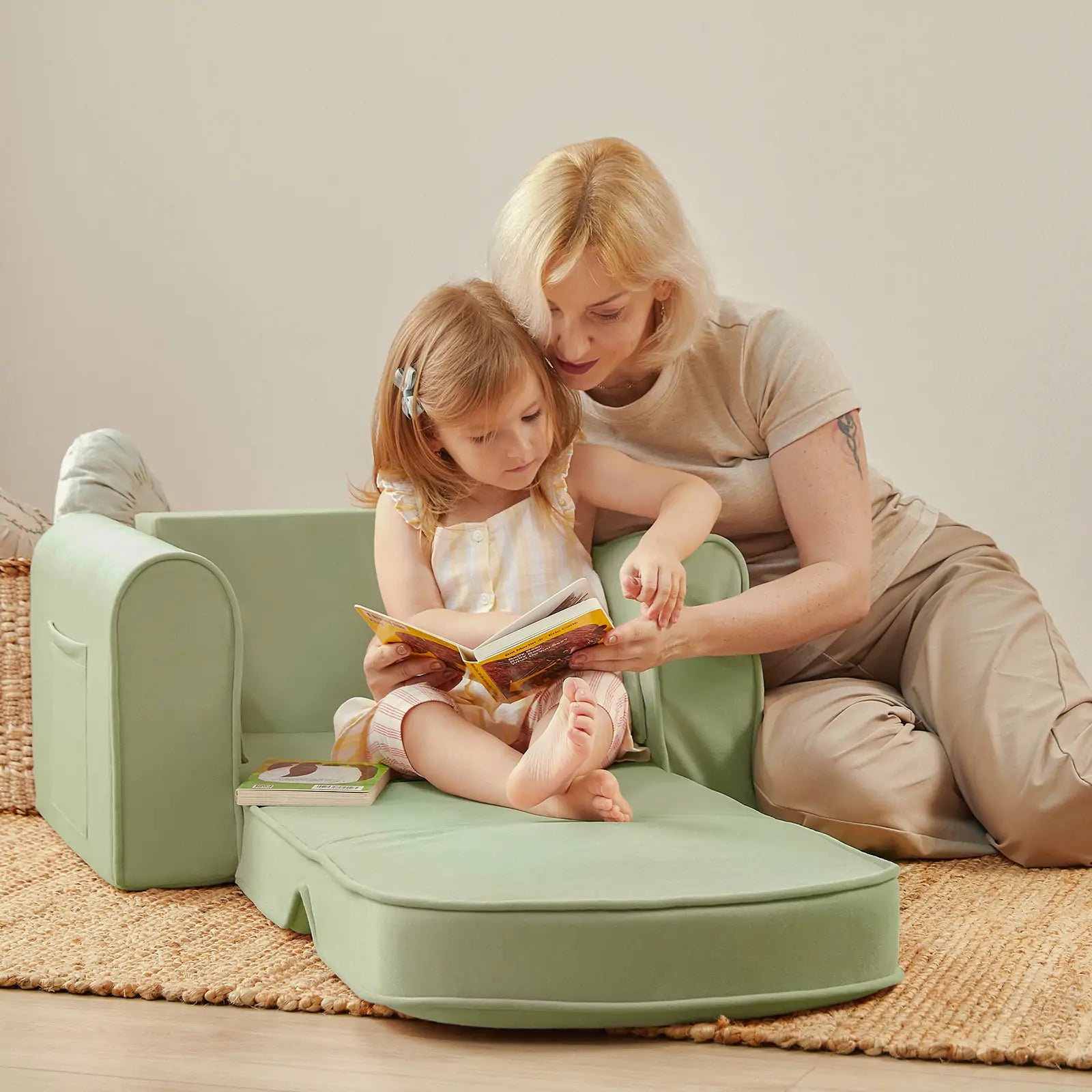 Tiny Land GentleSnug sage kids sofa chair with side pocket holding a book