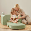 Tiny Land GentleSnug sage kids sofa chair with side pocket holding a book