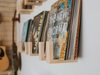Hardwood vinyl record wall shelf holding a collection of LP records with a guitar in the background