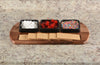 Wooden tray with graham crackers, white chocolate chips, red candies, and colorful sprinkles on a granite countertop.