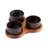 Three black ceramic cups on a wooden tray with a white background
