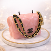 Pink Chanel handbag with black and gold chain on a white surface