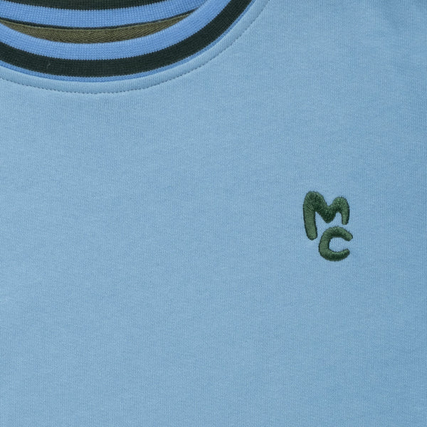 Close-up of Mon Coeur MC Blue Sweatshirt showing ribbed cuff and logo detail
