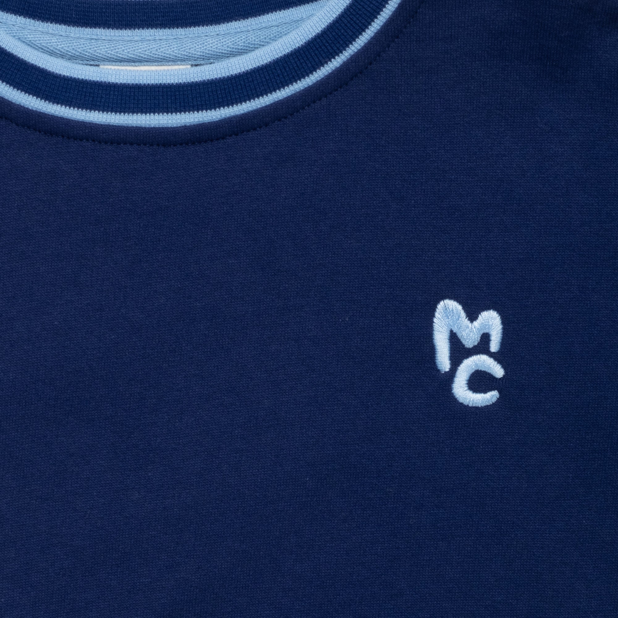 Close-up of Mon Coeur Kids MC Navy Sweatshirt showing signature MC logo and rib trim detail