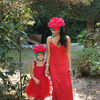 Woman and child in matching red outfits with floral headbands standing outdoors.