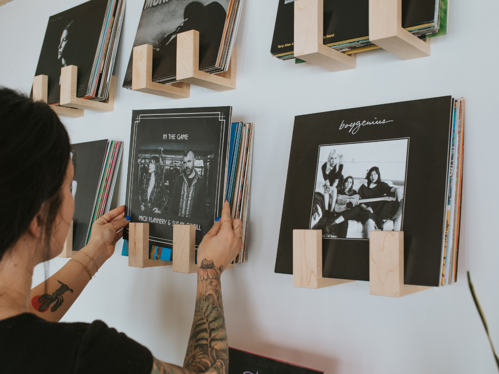 Person arranging vinyl records on a wall with wooden stands