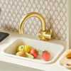 Children's toy kitchen set with a gold faucet and sink against a patterned wall.