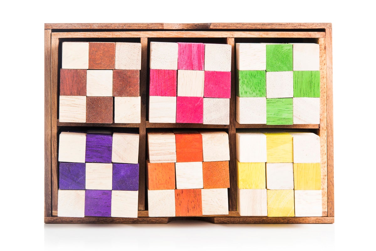 Wooden box with compartments containing colorful square blocks on a white background