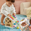 Child playing with a colorful wooden toy house on a blue rug.