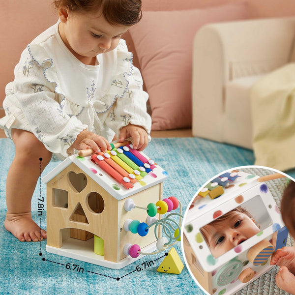 Child playing with a colorful wooden toy house on a blue rug.