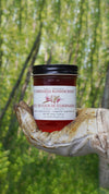 Jar of Julbernardia Blossom Honey held by a hand against a blurred natural background
