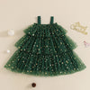 A green tiered tulle dress with gold star patterns, displayed flat on a beige background with Christmas-themed decorative props.