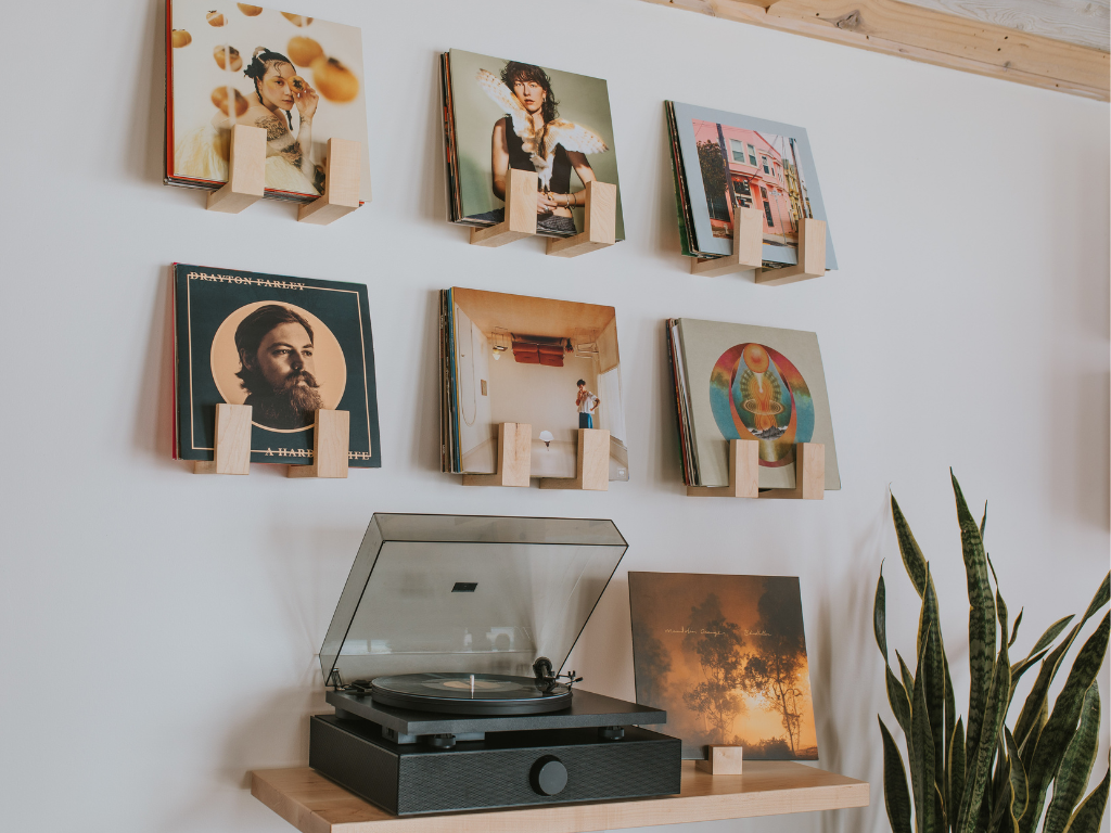 Record player with vinyl records on a wall display against a white wall.