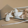 White ceramic unicorn and duck figurines on a reflective surface with a neutral background