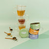 Tea-making setup with cups, tea leaves, and containers on a light green background