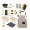 Collection of kitchen items including a hat, apron, bowls, and utensils on a white background.