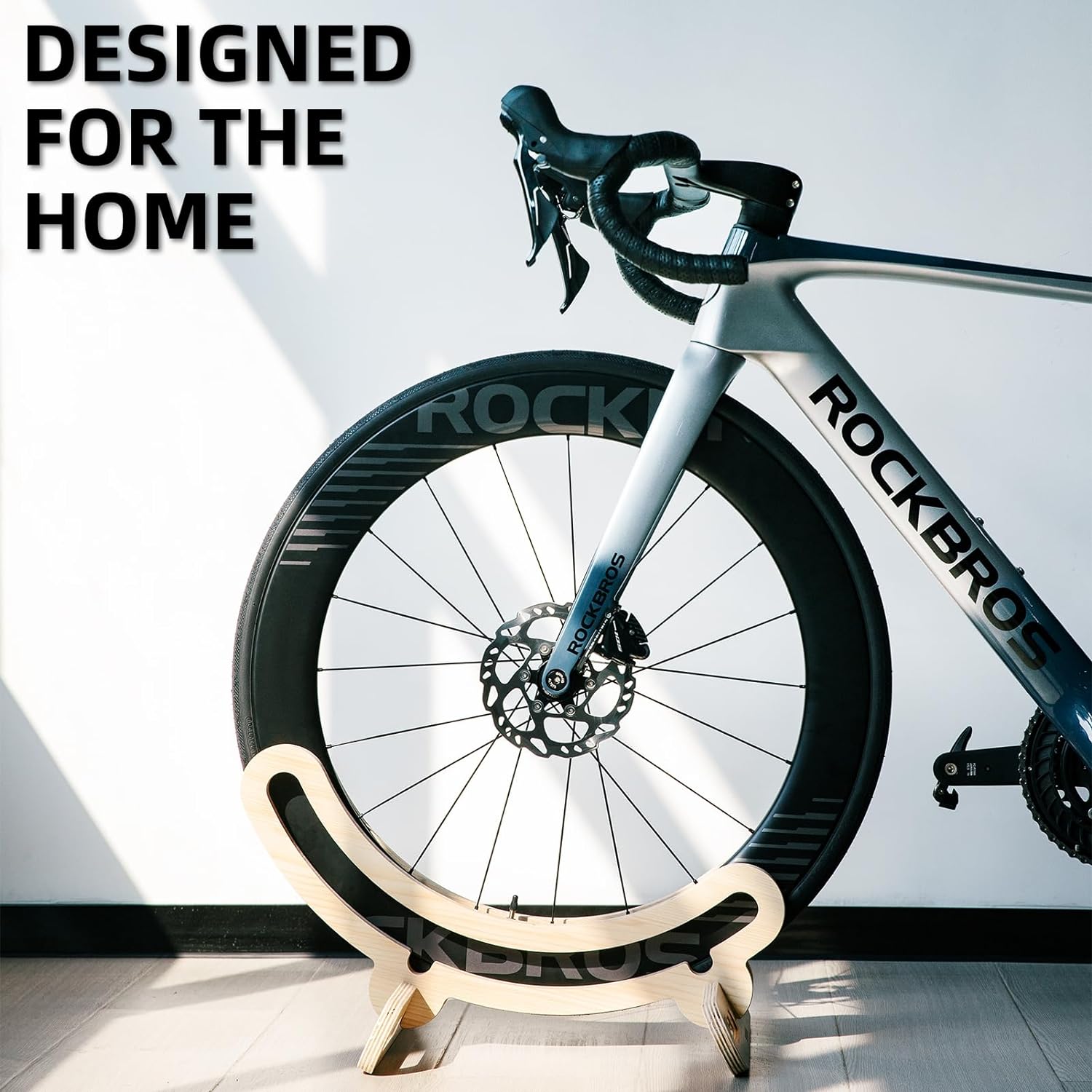 Bicycle on a stand with 'Rockbro' branding against a light background. ROCKBROS wooden bike stand — tool-free 2-min assembly, fits most road bikes, eco-friendly natural wood. Stable, portable & stylish. Perfect cyclist gift. Shop now.