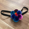 Colorful pom-pom hair tie on a wooden surface