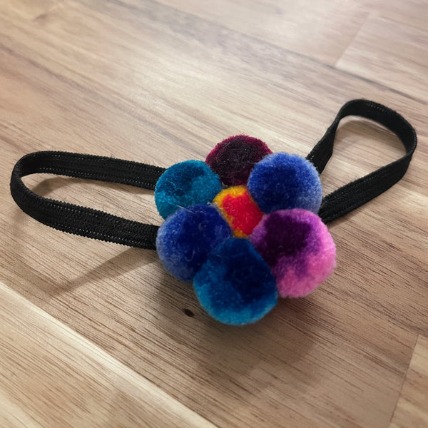 Colorful pom-pom hair tie on a wooden surface