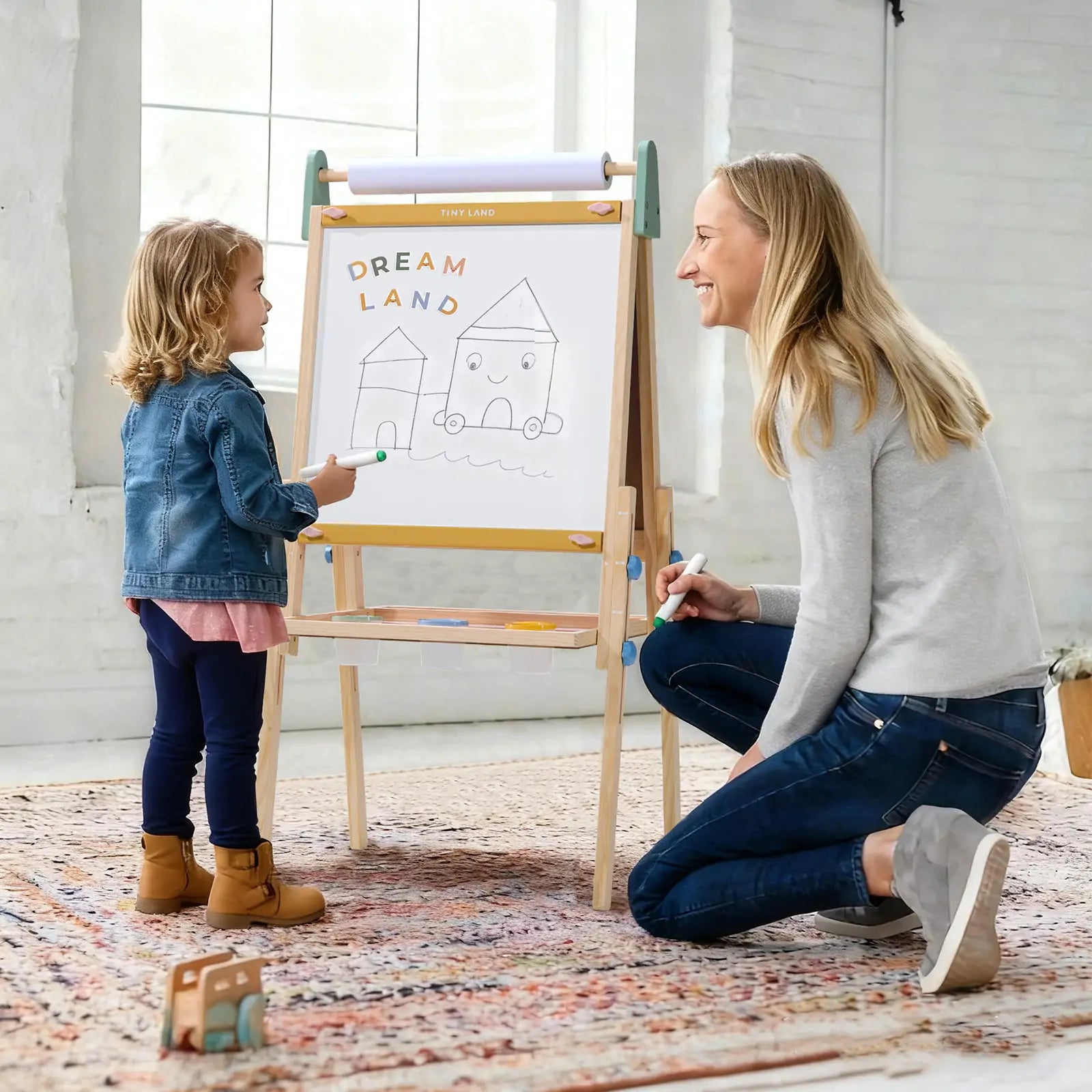 Woman and child drawing on a whiteboard together in a bright room.