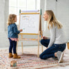 Woman and child drawing on a whiteboard together in a bright room.